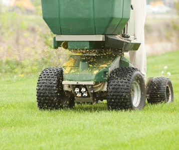 Machine placing fertilizer on lawn